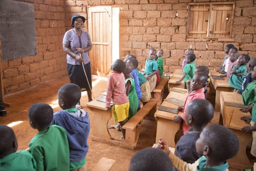 A teacher of a level one multi-lingual class leads the class in a song about the days of the week. The Multi-lingual school allows students to learn in their mother tongue before teaching them the the national languages of English or French.