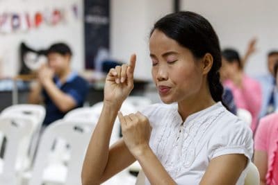 A Deaf woman prays during a church service at Grace Era Club Church in Bangkok, Thailand.